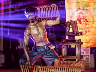 Foto ini diambil pada 11 Agustus 2025 menunjukkan seorang pekerja pabrik genteng yang berpose sambil memegang genteng selama kompetisi binaraga tradisional di pabrik genteng di Jatiwangi, Majalengka, Jawa Barat. (Aditya Irawan/AFP)