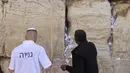 Pekerja Tembok Barat menghapus pesan dan doa, yang ditulis di selembar kertas oleh ribuan orang yang "ditujukan kepada Tuhan", dari celah-celah situs suci Yahudi di Kota Tua Yerusalem (30/3/2022). Pembersihan sebagai persiapan untuk liburan Paskah Yahudi yang akan datang. (AFP/Hazem Bader)