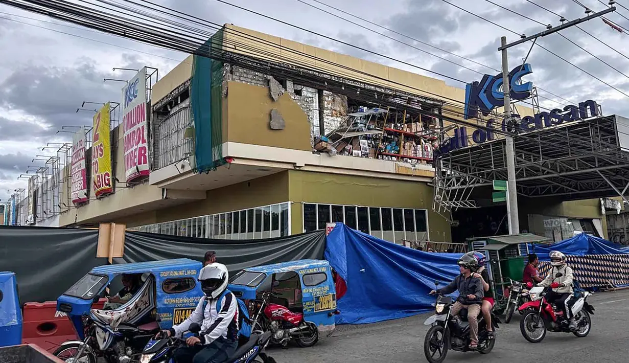 Pengendara berjalan melewati gedung yang rusak setelah gempa bumi berkekuatan magnitudo 7,8 di Kota General Santos, Filipina, pada Senin 8 Juni 2026. (Edwin Espejo/AFP)