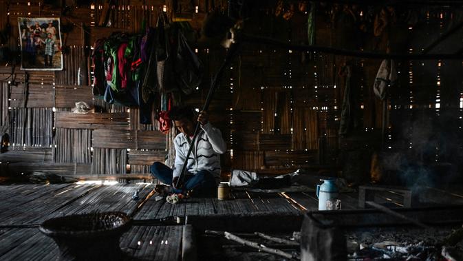 Seorang anggota suku Naga memeriksa senapan berburu tua dalam rumahnya di sebuah desa di wilayah Sagaing, Myanmar, 4 Februari 2020. Tato bisa menandakan identitas suku, pencapaian kehidupan atau penyelesaian ritual perjalanan. (Ye Aung THU/AFP)