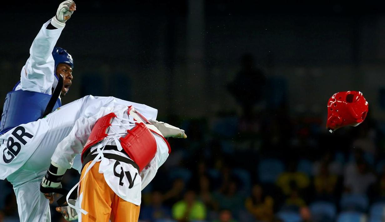  Helm taekwondoin Pantai Gading, Cheikh Sallah Cisse, terlepas setelah terkena tendangan atlet Inggris Raya, Lutalo Muhammad (kiri), dalam final kelas -80kg Olimpiade Rio 2016 di Rio de Janeiro, Brasil, (19/8/2016). (Reuters/Peter Cziborra)