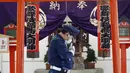 Seorang petugas keamanan yang mengenakan masker pelindung untuk membantu mengekang penyebaran virus corona COVID-19 berjalan di depan sebuah kuil di Tokyo, Jepang, Kamis (15/4/2021). Tokyo mengonfirmasi lebih dari 700 kasus baru COVID-19 pada 15 April 2021. (AP Photo/Eugene Hoshiko)