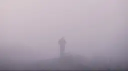 Seorang pria berjalan saat kabut tebal melanda kota Pristina (17/12/2019). Selama beberapa bulan terakhir Pristina terdaftar sebagai salah satu kota yang mengalami kualitas udara terburuk di dunia. (AFP/Armend Nimani)