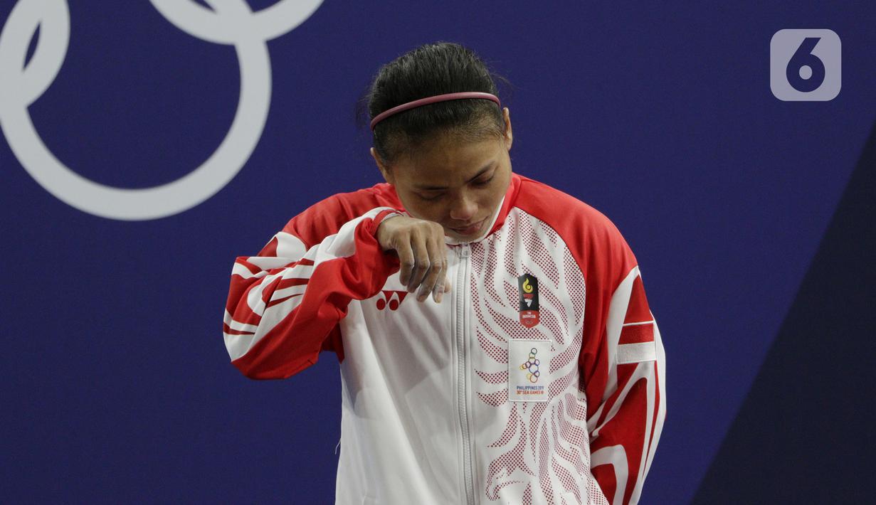 Lifter putri Indonesia, Lisa Setiawati menangis saat naik podium usai mendapatkan medali perak SEA Games 2019 cabang angkat besi nomor 45 kg di Stadion Rizal Memorial, Manila, Minggu (1/12/2019). Dirinya meraih perak dengan total angkatan 169 kg. (Bola.com/M Iqbal Ichsan)