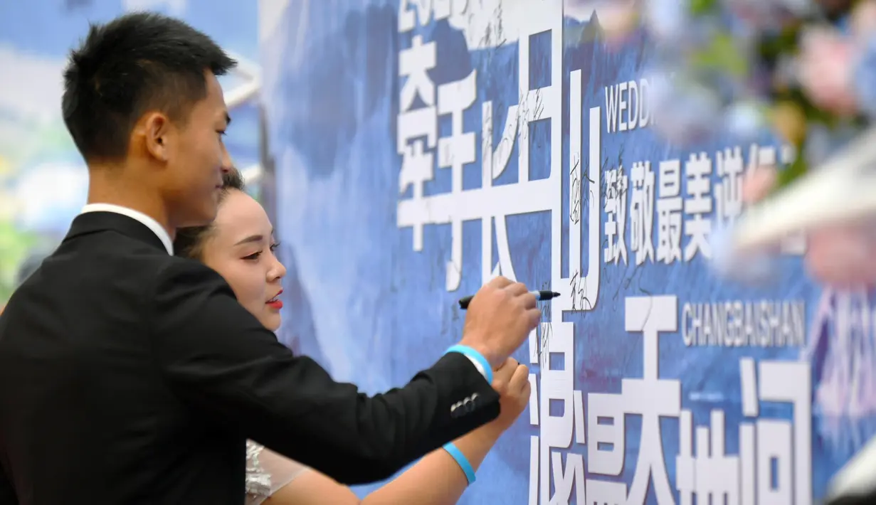 Pasangan yang bergabung dalam perjuangan melawan COVID-19 membubuhkan tanda tangan saat nikah massal di Provinsi Jilin, China, Rabu (8/7/2020). Nikah massal ini dihelat untuk 50 pasangan dari seluruh China yang telah berjuang melawan COVID-19 dan menunda pernikahan mereka. (Xinhua/Lin Hong)