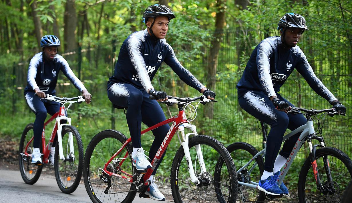 Pemain Prancis, Kylian Mbappe dan Paul Pogba, bersepeda di sekitar markas latihan Les Blues di Clairefontaine, Rabu (23/5/2018). Bersepeda merupakan salah satu menu latihan untuk meningkatan kebugaran jelang Piala Dunia 2018. (AFP/Franck Fife)