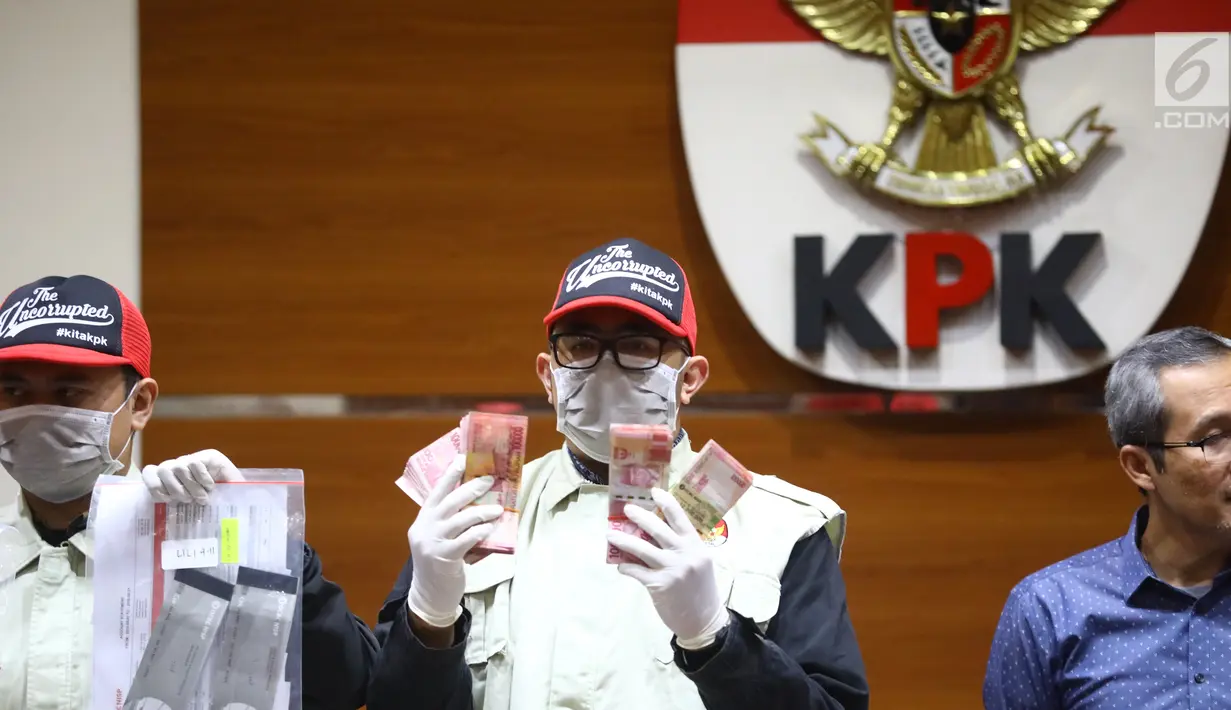Petugas menunjukkan barang bukti Rp1,2 miliar disaksikan Wakil Ketua KPK Alexander Marwata saat keterangan pers OTT penanganan perkara penyalahgunaan izin tinggal Kantor Imigrasi Kelas I Mataram, NTB di Gedung KPK, Jakarta (28/5/2019). (Liputan6.com/Johan Tallo)