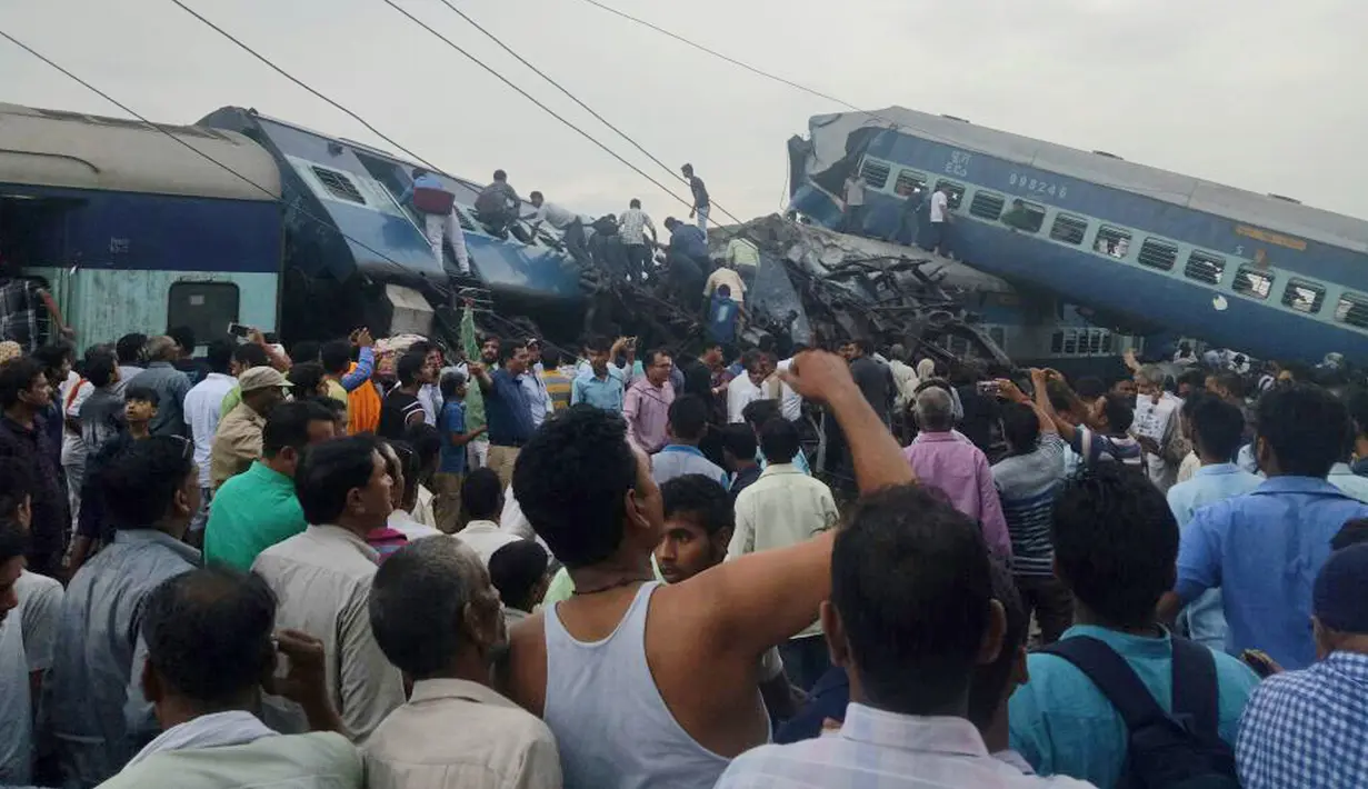 Polisi dibantu warga lokal mengevakuasi para korban dari sebuah kereta api yang tergelincir hingga keluar jalur di Negara Bagian Uttar Pradesh, India, Minggu (20/8). Sedikitnya lebih dari 20 penumpang tewas akibat kecelakaan tersebut. (AP Photo)