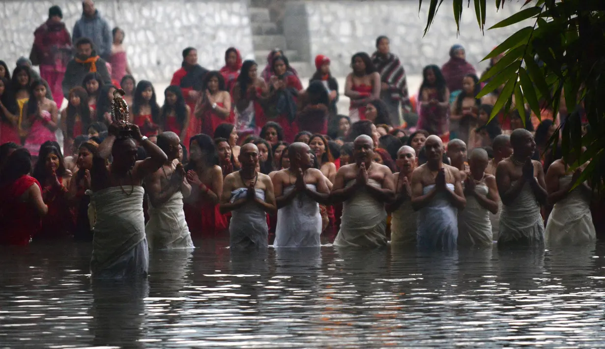 Umat Hindu Nepal berkumpul untuk mandi di Sungai Shali di pinggiran Kathmandu, Nepal, (24/1). Selama festival ini, para wanita yang belum menikah berdoa untuk mendapatkan suami yang baik. (AFP PHOTO/Prakash mathema)