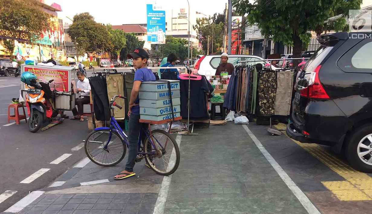 PKL menutup sebagian badan trotoar di kawasan Jatinegara, Jakarta, Senin (24/9). Kondisi trotoar yang telah diperlebar Pemprov DKI Jakarta kini dipenuhi PKL dan parkir liar sehingga mengganggu kenyamanan pejalan kaki. (Liputan6.com/Immanuel Antonius)