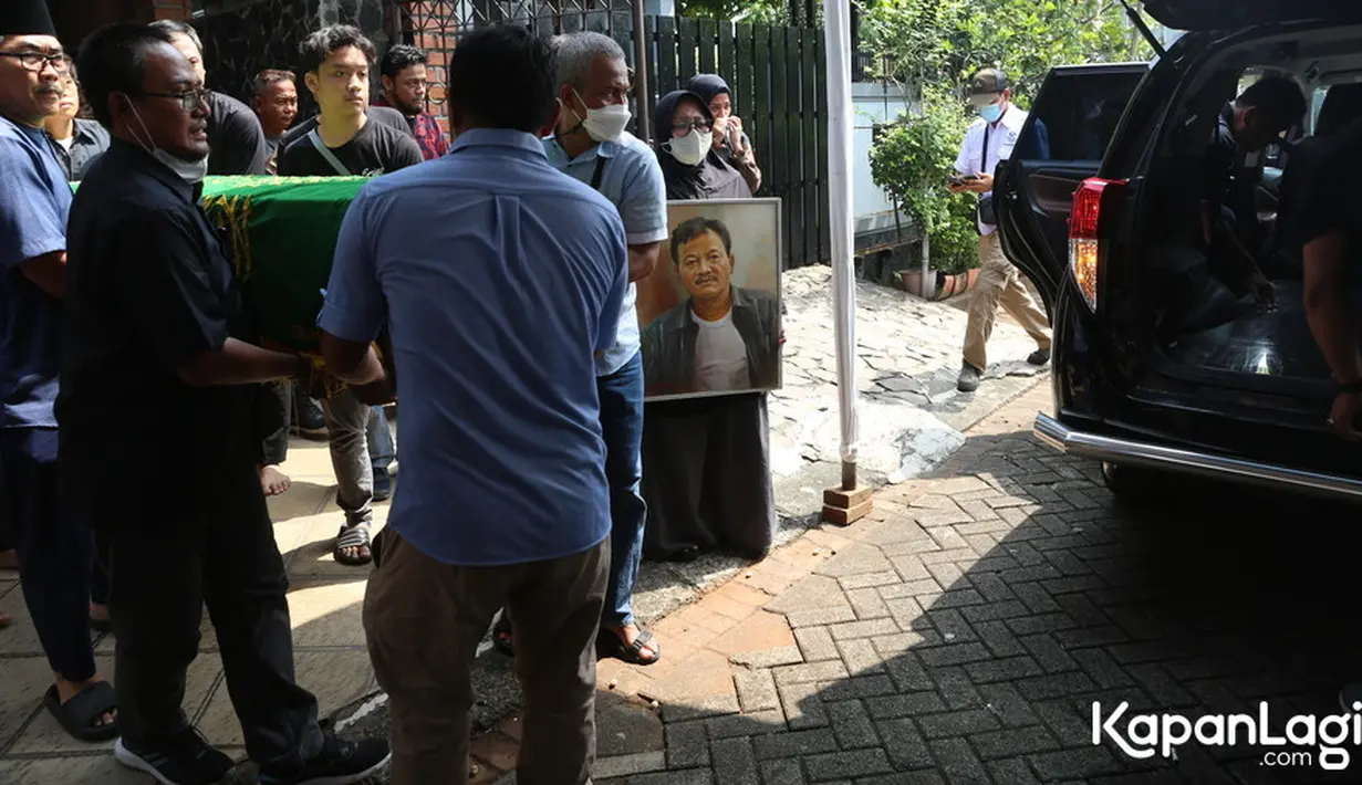 Seorang perempuan membawa foto aktor yang sukses memerankan peran antagonis ini. Jenazah saat akan meninggalkan kediamannya untuk di makamkan. Sebuah mobil ambulance telah disiapkan. [Foto: Budy Santoso/KapanLagi.com]