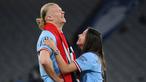 Pemain Manchester City, Erling Haaland, bercanda dengan kekasihnya Isabel Haugseng Johansen saat perayaan gelar juara Liga Champions di Ataturk Olympic Stadium, Istanbul, Minggu (11/6/2023). Erling Haaland tampil luar biasa dan mampu meraih treble winner di musim perdananya bersama City. (AFP/Franck Fife)