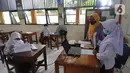 Murid kelas IV menunjukkan hasil tesnya kepada teman-temannya yang belajar online di rumah saat kegiatan belajar tatap muka di SDN Pondok Labu 14 Pagi di Cilandak, Jakarta Selatan, Jumat (4/6/2021). (merdeka.com/Arie Basuki)