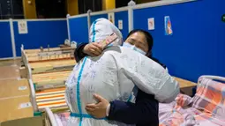 Pasien virus corona atau COVID-19 Ying memeluk petugas medis Cao Jinglei di sebuah rumah sakit sementara di Wuhan, China, Senin (9/3/2020). China menutup semua rumah sakit sementara yang dibuat untuk menangani virus corona di Kota Wuhan.  (Xinhua/Shen Bohan)