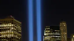 Sorotan cahaya kembar berwarna biru untuk peringati peristiwa serangan 9/11 di Kota New York, Minggu (10/9). Dua cahaya biru tegak lurus itu melambangkan menara kembar WTC yang menjadi sasaran serangan bunuh diri tersebut. (AP Photo/Mark Lennihan)