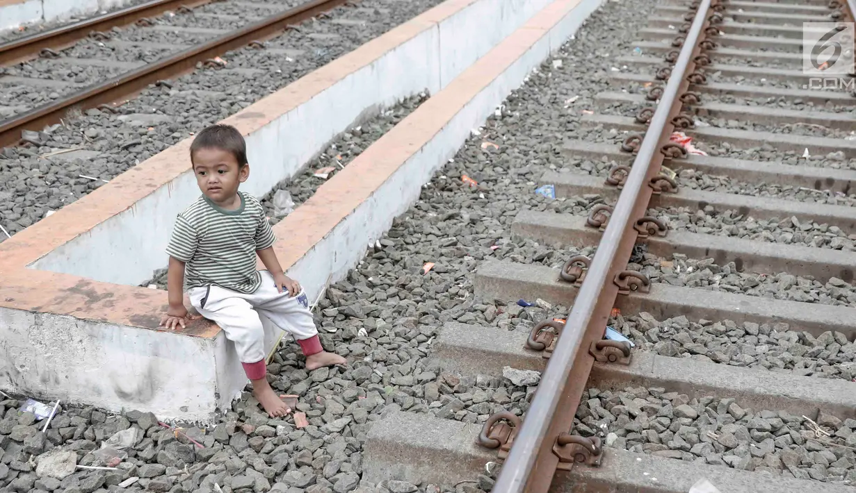 Seorang anak duduk di sekitar rel kereta api di kawasan Pademangan, Jakarta, Kamis (8/11). Kurangnya lahan bermain menyebabkan anak-anak tersebut bermain di tempat yang tidak semestinya dan membahayakan. (Liputan6.com/Immanuel Antonius)