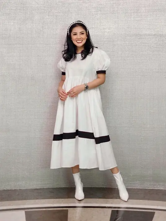 Nindy Ayunda memadukan gaya dewasa dan anak-anak dalam satu tampilan. Mengenakan ankle boots berwarna putih, Nindy memadukannya dengan dress A-Line putih bergaris hitam dengan detail puff di bagian lengan. (instagram/nindyayunda)