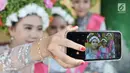 Sejumlah gadis berswafoto saat menunggu upacara adat Ngarot dimulai di Desa Lelea, Indramayu, Jawa Barat, Rabu (19/12). Hari Rabu minggu ketiga di bulan Desember dipercaya oleh masyarakat setempat sebagai hari keramat. (Merdeka.com/Iqbal Nugroho)
