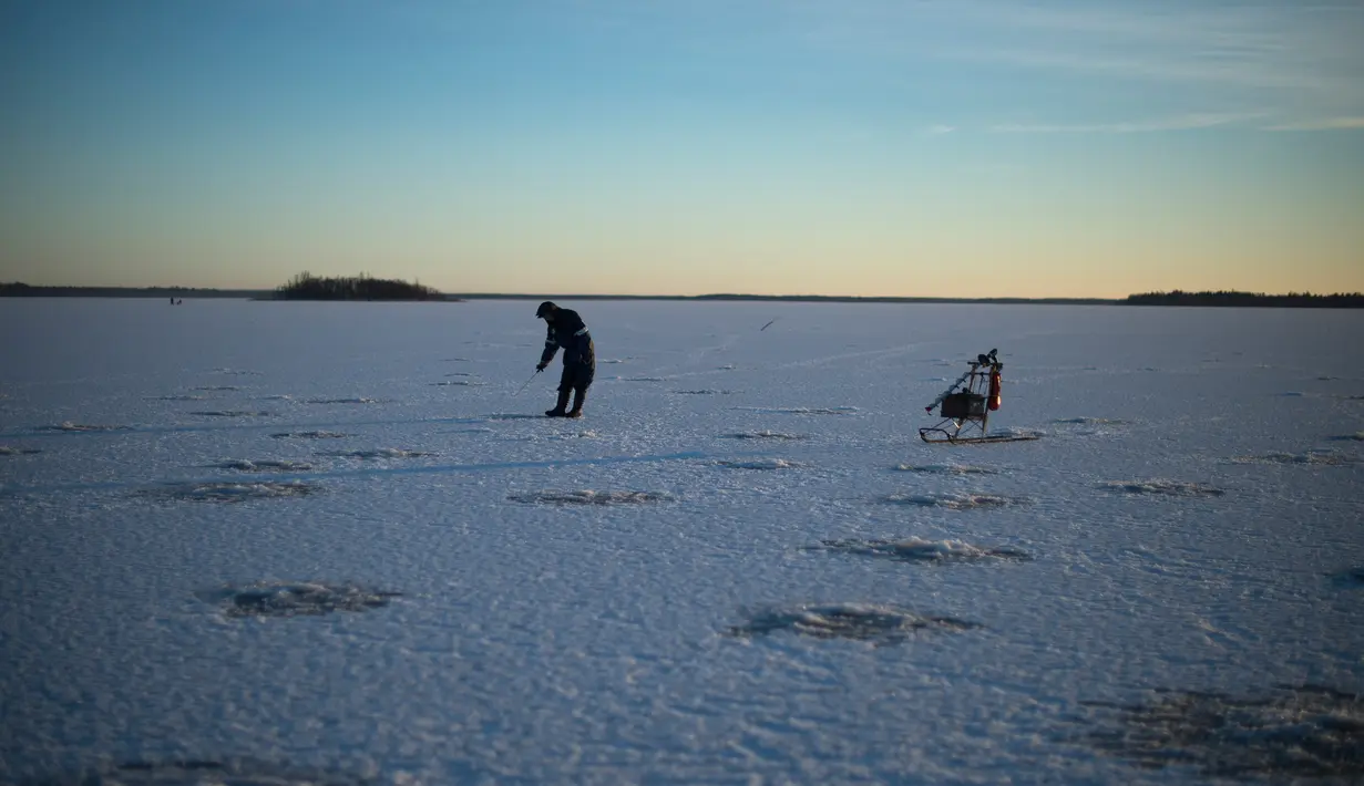 Seorang pria berusaha memancing ikan di laut Bothnia yang sedang membeku, Vaasa, Finlandia (29/12). Kebiasaan memancing di laut beku merupakan hal menantang yang ditunggu-tunggu oleh sebagian warga setempat. (AFP PHOTO/Olivier Morin)