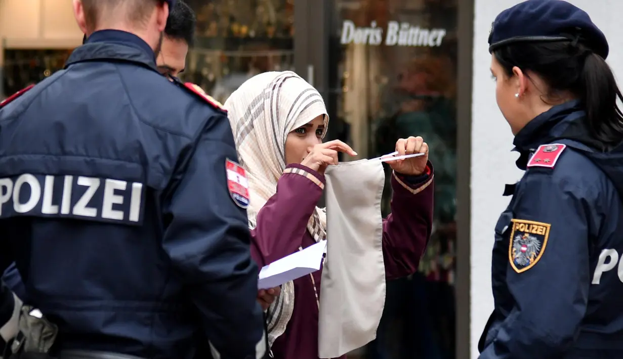 Seorang wanita Muslim dipaksa oleh Polisi Austria melepaskan cadarnya di kota Zell am See, Minggu (1/10). Undang-undang di Austria menyebutkan bahwa menutupi wajah di tempat umum akan dikenai sanksi dan denda sekira Rp2,4 juta. (BARBARA GINDL/APA/AFP)