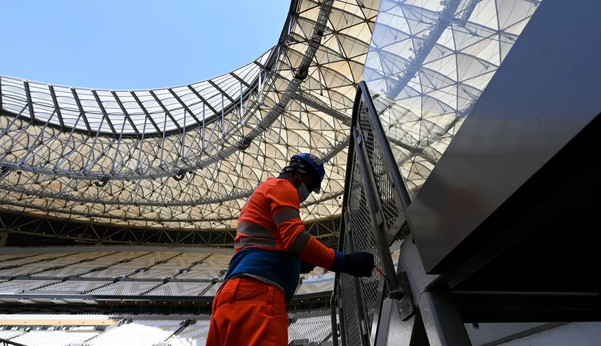 Seorang pria bekerja di lapangan Lusail Stadium, Lusail, Qatar, 28 Maret 2022. Stadion berkapasitas 80 ribu penonton yang terletak di pinggiran Ibu Kota Doha ini akan menjadi tuan rumah final Piala Dunia 2022 pada bulan Desember mendatang. (GABRIEL BOUYS/AFP)