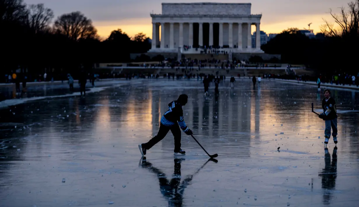 Lincoln Memorial terlihat saat bersaudara Jacek Zavora (21) dan Zach Zavora (10) dari Arlington bermain hoki di Reflecting Pool yang membeku, National Mall, Washington, Amerika Serikat, 26 Desember 2022. (AP Photo/Andrew Harnik)