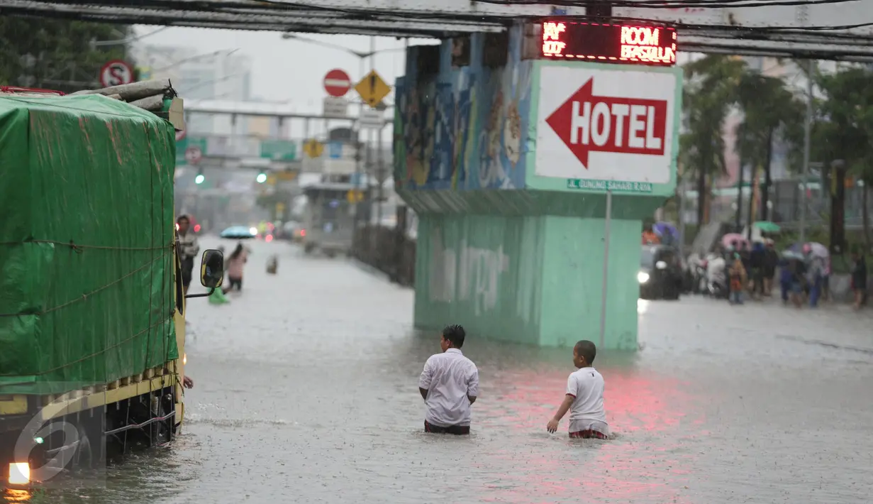 Dua orang anak bermain banjir yang merendam Jalan Gunung Sahari, Pademangan, Jakarta Pusat, Selasa (21/2). Hujan yang turun sejak dini hari menyebabkan sejumlah ruas jalan terimbas banjir hingga tak bisa dilalui kendaraan (Liputan6.com/Faizal Fanani)