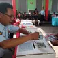 Seorang petugas Lapas Lowokwaru Malang membantu warga binaan memasukkan surat suara usai pencoblosan (Liputan6.com/Zainul Arifin)