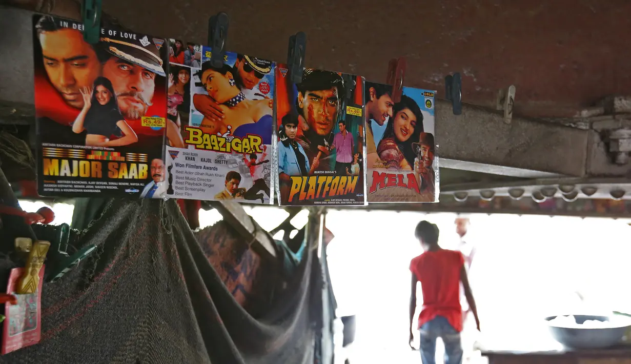 Seorang pria berjalan ke luar bioskop darurat di bawah jembatan di India (25/5). Untuk menghibur warga kurang mampu yang menyukai musik dan film Bollywood, tempat ini menayangkan sebanyak 4 film dalam sehari. (REUTERS/Cathal McNaughton)