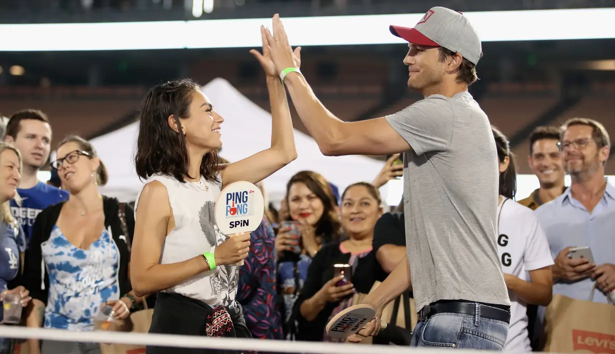 Pasangan selebriti, Mila Kunis (kiri) dan Ashton Kutcher (kanan) salam tos saat bermain pingpong di acara tahunan ke-6 dari Clayton Kershaw, Ping Pong 4 Purpose, Los Angeles, Amerika Serikat, Kamis (23/8). (CHRISTOPHER POLK/GETTY IMAGES NORTH AMERICA/AFP)