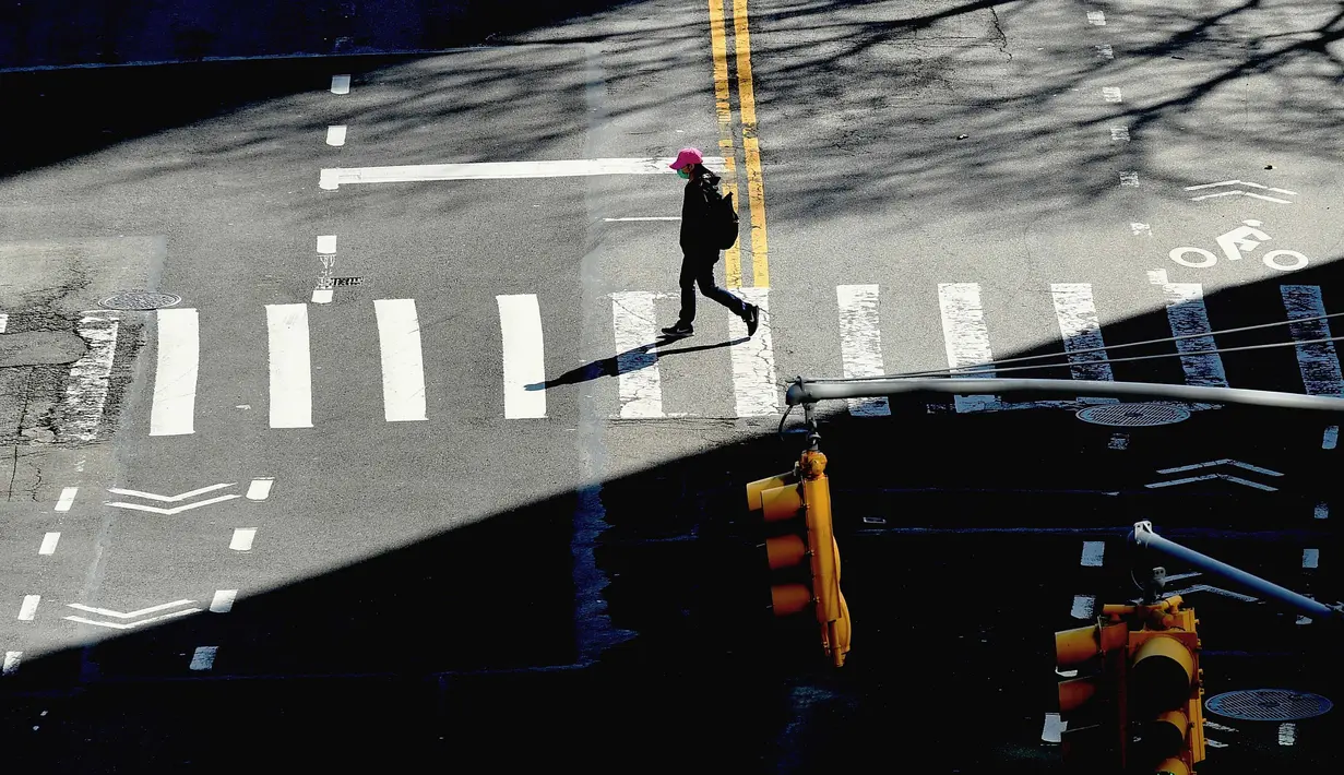 Seseorang melintasi jalan di New York City pada 27 Maret 2020. Selain mencatatkan jumlah kasus virus corona Covid-19 tertinggi di dunia, Amerika Serikat (AS) juga catatkan jumlah pengajuan tunjangan pengangguran tertinggi di negaranya. (Photo by Angela Weiss / AFP)