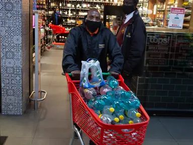 Pelanggan meninggalkan toko minuman keras dengan belanjaannya ketika Afrika Selatan mencabut larangan penjualan alkohol dan rokok di Johannesburg, Selasa (18/8/2020). Pembelian alkohol dan rokok dilarang ketika Afrika Selatan memberlakukan lockdown ketat pada 27 Maret 2020. (AP Photo/Denis Farrell)