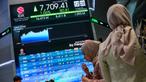 Orang-orang berdiri di samping layar yang menampilkan angka-angka perdagangan saham di gedung Bursa Efek Indonesia di Jakarta pada Rabu 10 September 2025. (BAY ISMOYO/AFP)