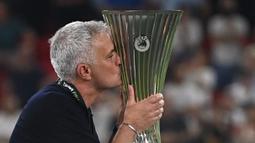 Pelatih kepala AS Roma, Jose Mourinho mencium trofi EUFA Confernce League usai berhasil membawa AS Roma mengalahkan Feyenoord dengan skor 1-0 pada laga final yang berlangsung di Stadion Arena Kombetare Tirana, Albania, pada Kamis (26/5/2022) dini hari WIB. Bagi Mourinho, trofi ini menjadi gelar juara Eropa-nya yang kelima. (AFP/Ozan Kose)