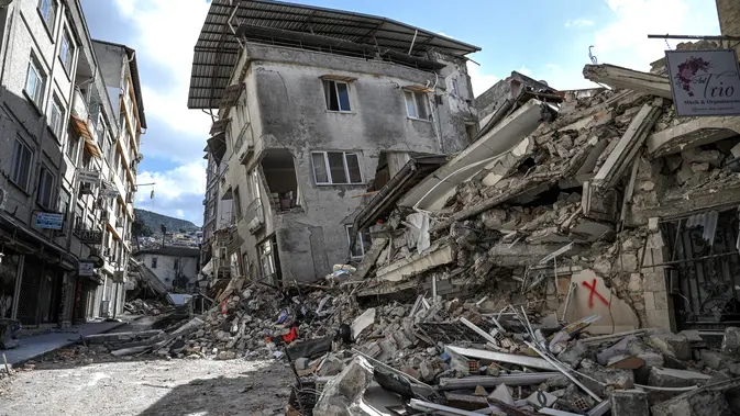 Gambar ini memperlihatkan bangunan yang hancur di Hatay pada 6 Maret 2023, satu bulan setelah gempa besar melanda Turki tenggara. Gempa bumi besar berkekuatan magnitudo 7,8 mengguncang sebagian besar Turki dan sebagian Suriah pada 6 Februari 2023, menewaskan lebih dari 50.000 orang di kedua negara, dengan sekitar 46.000 di pihak Turki. (OZAN KOSE / AFP)