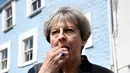 Perdana Menteri (PM) Inggris, Theresa May mencicipi beberapa keripik saat berhenti untuk kampanye di Mevagissey, Cornwall, Selasa (2/5). Theresa May melakukan kampanye dengan berkeliling jalanan di Cornwall. (AFP PHOTO/POOL/DYLAN MARTINEZ)