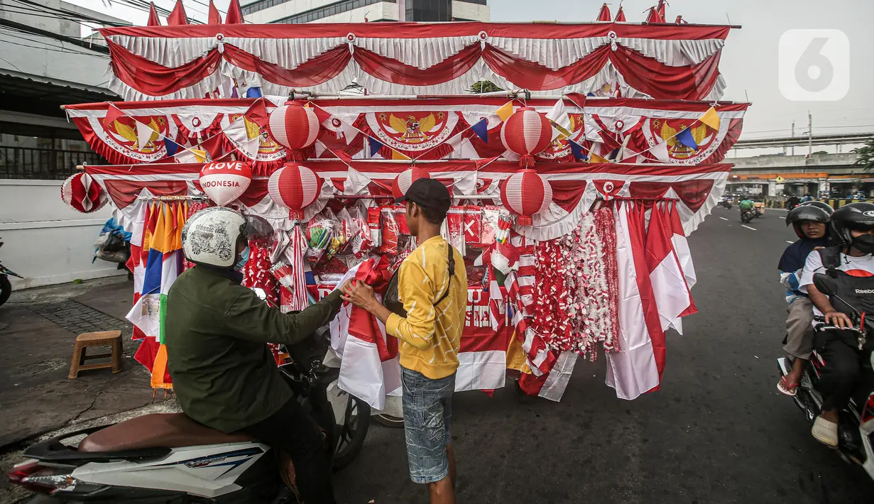 Seorang pedagang bendera merapikan umbul-umbul dan bendera yang di jual di Sepanjang Jalan Jatinegara, Jakarta, Selasa (2/8/2022). Jelang peringatan HUT Kemerdekaan RI ke-77, pedagang musiman bendera  mulai bermunculan mereka memanfaatkan trotoar untuk memajang dagangannya, mulai dari umbul-umbul, bendera, hingga ornamen khas merah putih lainnya dengan harga yang tawarkan juga bervariasi, mulai dari Rp. 5.000 ,- hingga Rp. 300.000,. (Liputan6.com/Faizal Fanani)