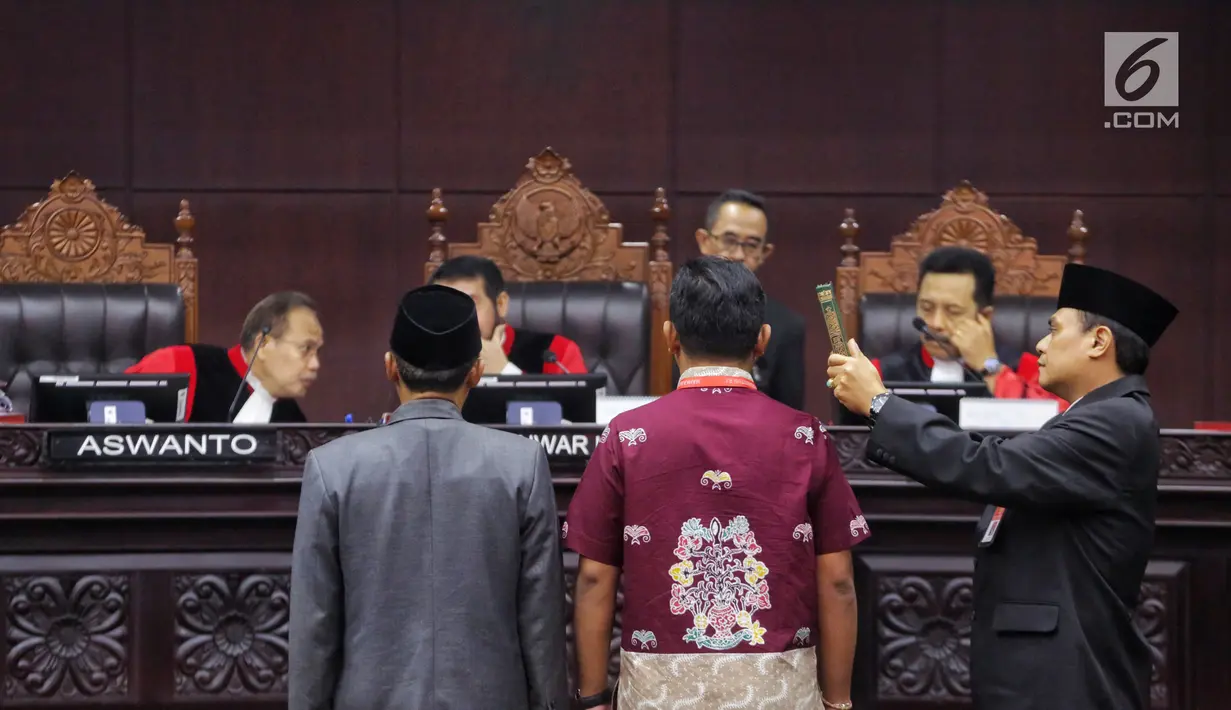 Saksi Tim Hukum Jokowi, Candra Irawan (baju batik) saat disumpah sebelum memberikan kesaksian di hadapan hakim konstitusi dalam sidang lanjutan sengketa Pilpres 2019 di Gedung MK, Jakarta, Jumat (21/6/2019). Candra merupakan tenaga ahli di Fraksi PDI Perjuangan. (Liputan6.com/Johan Tallo)
