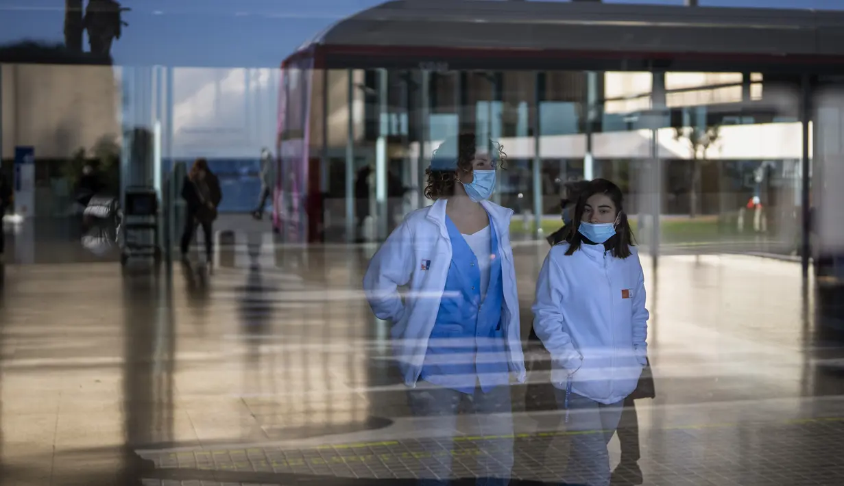 Orang-orang yang memakai masker sebagai tindakan pencegahan berjalan di dalam rumah sakit di Barcelona, ​​Spanyol, Senin (8/1/2024). (AP Photo/Emilio Morenatti)
