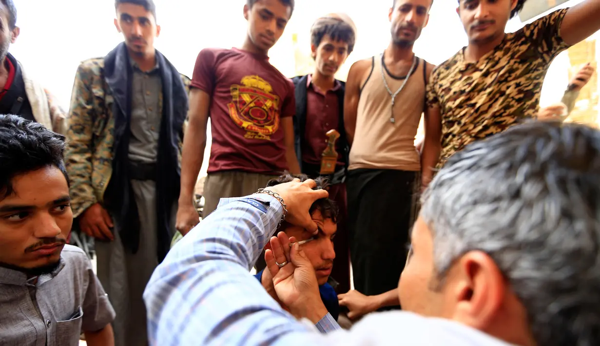 Seorang pria Yaman mengoleskan kosmetik tradisional kohl ke kelopak mata pria lain di Masjid Agung, kota tua Sanaa pada 9 mei 2019. Bagi muslim Yaman, pemakaian kohl diyakini mampu membersihkan dan melindungi mata dari penyakit ini sudah menjadi tradisi setiap bulan Ramadan. (MOHAMMED HUWAIS/AFP)