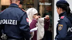 Seorang wanita Muslim dipaksa oleh Polisi Austria melepaskan cadarnya di kota Zell am See, Minggu (1/10). Undang-undang di Austria menyebutkan bahwa menutupi wajah di tempat umum akan dikenai sanksi dan denda sekira Rp2,4 juta. (BARBARA GINDL/APA/AFP)
