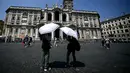 Dua orang membuka payung untuk melindungi diri dari terik matahari saat berdiri di depan Basilika Santa Maria Maggiore di pusat kota Roma pada 11 Agustus 2025. (Filippo MONTEFORTE/AFP)