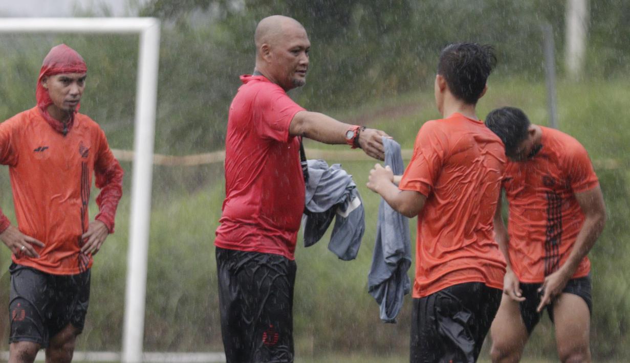 Asisten pelatih Persija Jakarta, Sudirman, memberikan rompi kepada pemain saat latihan di Lapangan NYTC, Sawangan, Depok, Kamis (16/1/2020). Hujan deras beserta petir membuat latihan Persija Jakarta kali ini hanya berlangsung sekitar 25 menit. (Bola.com/M Iqbal Ichsan)