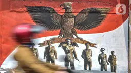 Pengendara melintas di depan mural bertemakan Pancasila di Kampung Pancasila kawasan Galur, Johar Baru, Jakarta, Selasa (1/6/2021). Mural di Kampung Pancasila ini juga untuk mempercantik lingkungan.tersebut. (merdeka.com/Iqbal S. Nugroho)