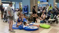 Para turis menunggu di aula keberangkatan bandara saat evakuasi sedang berlangsung akibat kebakaran hutan, di pulau Rhodes, Yunani, Minggu (23/7/2023). (Will VASSILOPOULOS / AFP)