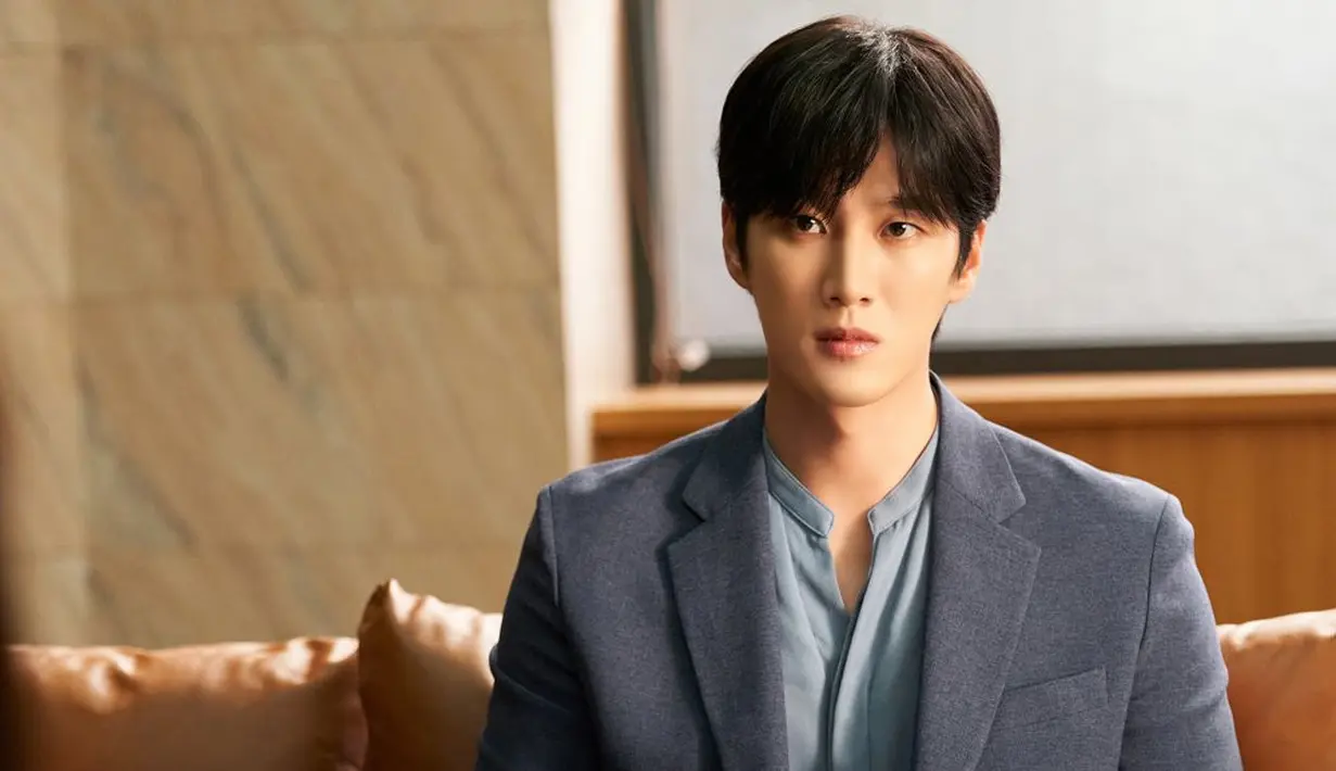 Dalam potongan gambar terbaru, Moon Seo Ha terlihat tampan dengan setelan jas. Dia tampak perfeksionis dengan postur duduknya yang tegak dan tatapan mata yang tajam. (Foto: tvN via Soompi)