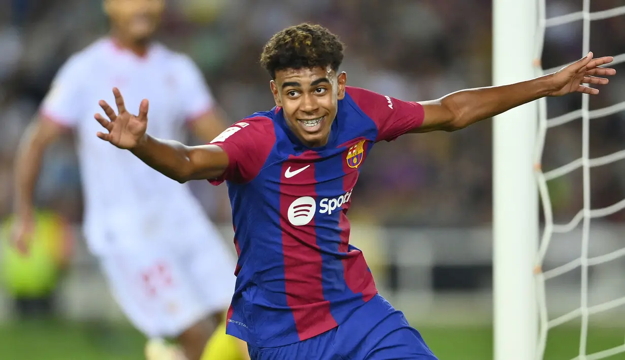 Pemain Barcelona, Lamine Yamal melakukan selebrasi setelah pemain Sevilla, Sergio Ramos mencetak gol bunuh diri pada laga lanjutan Liga Spanyol 2023/2024 melawan Barcelona di Estadi Olimpic Lluis Companys, Barcelona, Spanyol, Sabtu (30/09/2023) dini hari WIB. Gol bunuh diri Ramos berawal dari umpan silang Lamine Yamal. (AFP/Pau Barrena)