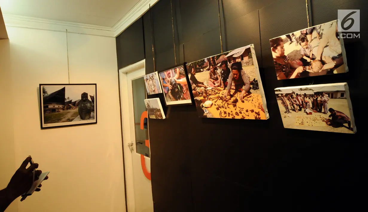 Pengunjung memotret deretan foto yang dipamerkan saat Peluncuran Buku Danau Toba dan Mangongkal Holi di Jakarta, Kamis (24/8). Pameran foto menampilkan kehidupan masyarakat dan budaya Batak. (LIputan6.com/Helmi Fithriansyah)
