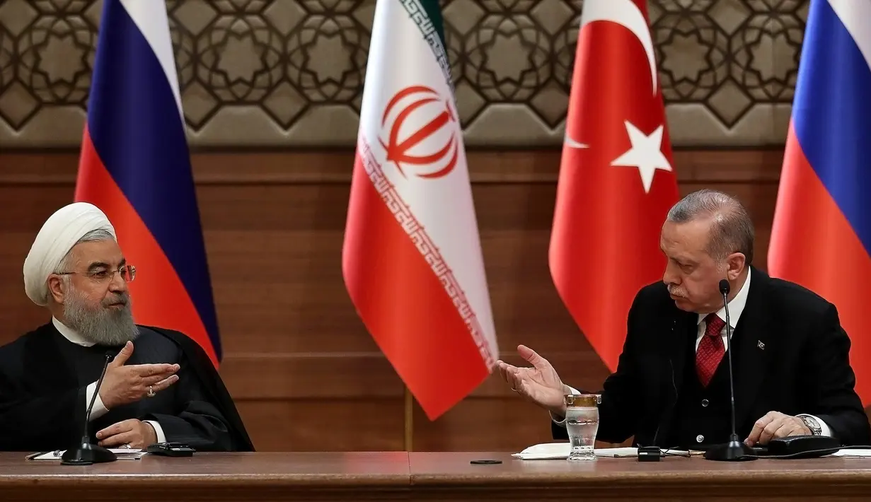 Presiden Turki Recep Tayyip Erdogan (kanan) dan Presiden Iran Hassan Rouhani (kiri) saat konferensi pers di Ankara, Turki, Rabu (4/4). Pertemuan ketiganya menghasilkan komitmen untuk mencapai gencatan senjata abadi di Suriah. (AFP PHOTO/ADEM ALTAN)