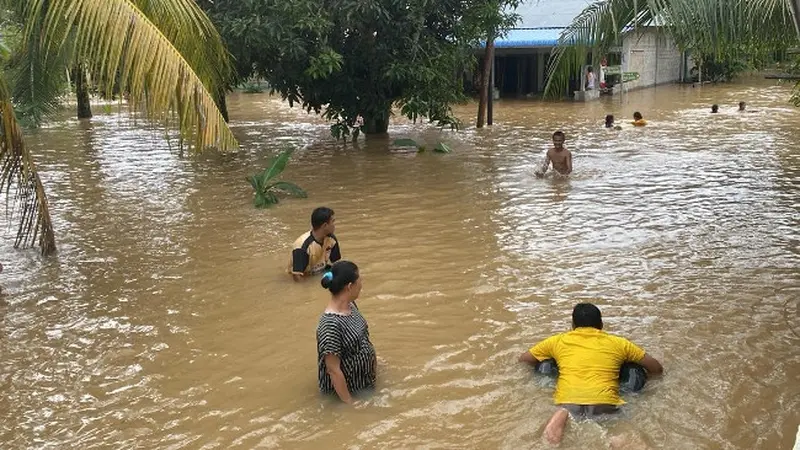 Masyarakat di Desa Talikumain, Kabupaten Rokan Hulu, keluar dari rumah memantau situasi banjir.